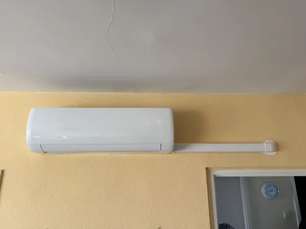 Beltéri egység sárga falon, kábelcsatornás vezetékkel
