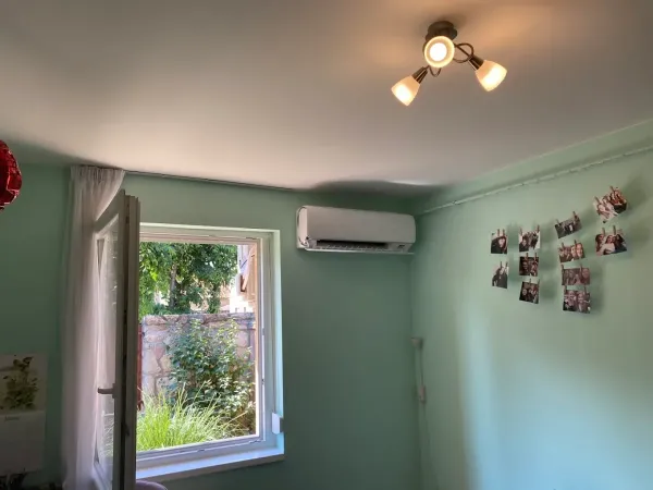 Beltéri egység zöld falú szobában, ablak fölött